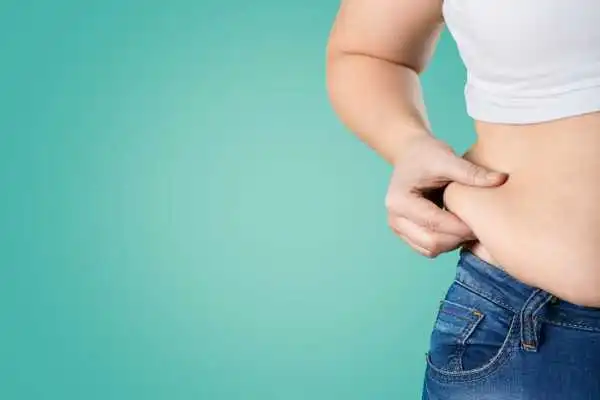 Image of woman pinching her love handles to show weight gain Westbury